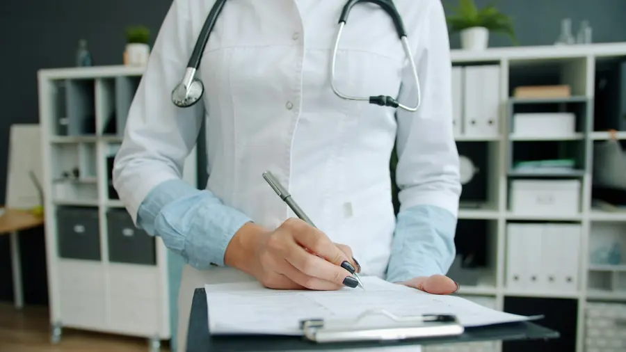 Médico con estetoscopio completando la historia clínica